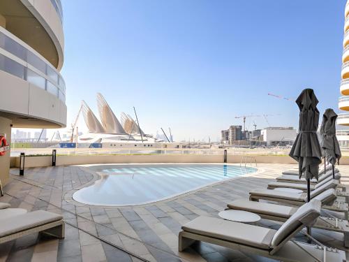 a swimming pool with chairs and umbrellas on a building at Desert Key Luxury Apt with Seaview, Saadiyat Island in Abu Dhabi