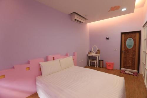 小琉球的住宿－幸福樂民宿，卧室配有白色的床和粉红色的墙壁
