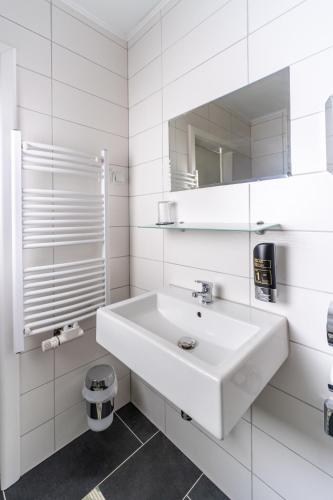 a white bathroom with a sink and a mirror at Hotel Lichtblick Salach in Salach
