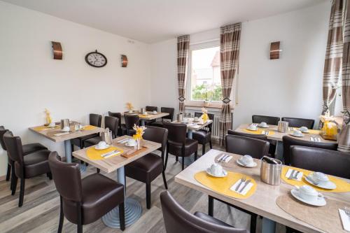 a restaurant with tables and chairs and a clock on the wall at Hotel Lichtblick Salach in Salach