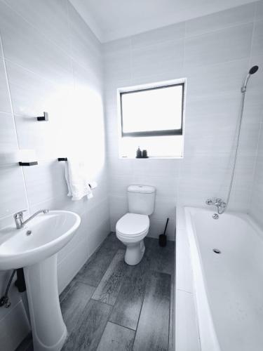 a white bathroom with a toilet and a sink at The Res Apartments in Maseru