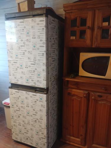 einen Kühlschrank neben einer Mikrowelle neben einem Schrank in der Unterkunft Cabaña La Florencia Domselaar in Domselaar