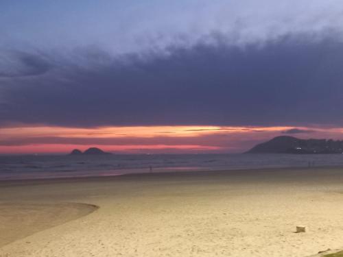 a view of a beach with a sunset in the background at Camping - Recanto do Leâo in Guarujá