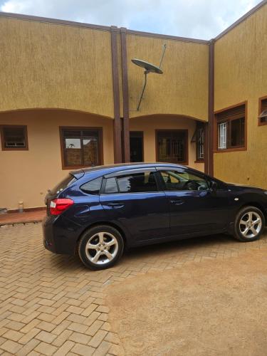 a blue car parked in front of a building at Lexus Guest House, Kasangati in Kampala