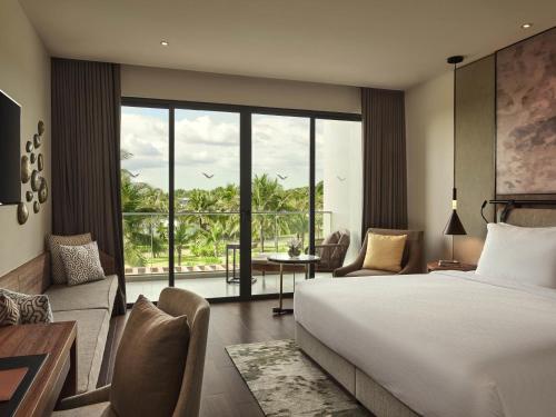 Un dormitorio con una cama y una sala de estar. en Mövenpick Resort Waverly Phu Quoc, en Phu Quoc