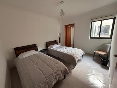 a bedroom with two beds and a chair and a window at Departamento a una cuadra del angel de la independencia in Mexico City