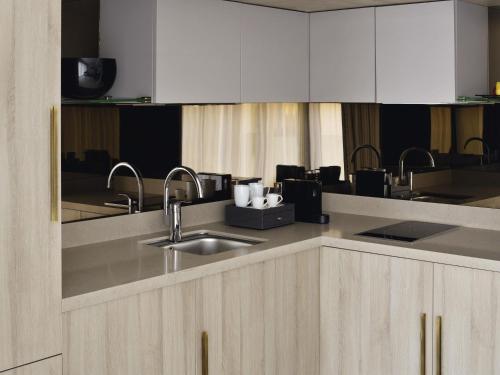 a kitchen with white cabinets and a sink at Mövenpick Hotel Tahlia Jeddah in Jeddah