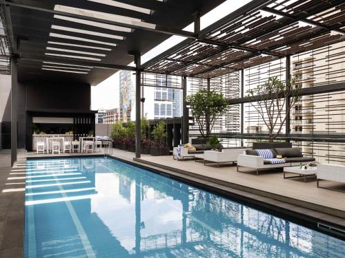a large swimming pool in a building with chairs and tables at Novotel Perth Murray Street in Perth