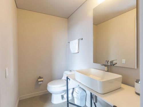 a bathroom with a white sink and a toilet at Hotel Bania travels in Guatapé