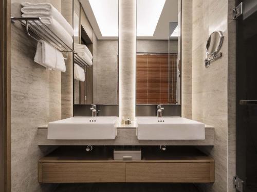deux lavabos dans une salle de bain avec deux miroirs dans l'établissement Ocean Spring Resort Chengdu - MGallery Collection, à Chengdu