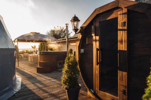 a wooden shed with a potted tree in a pot at Waterfront Glamping - Private hot tube, sauna & sunset view in Wapnica