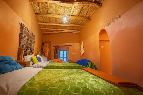 a bedroom with two beds with green and white at DAR Moha dades in Aït Ougliff