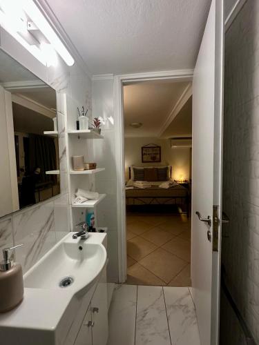 a white bathroom with a sink and a mirror at Adrianas Central Stay in Patra