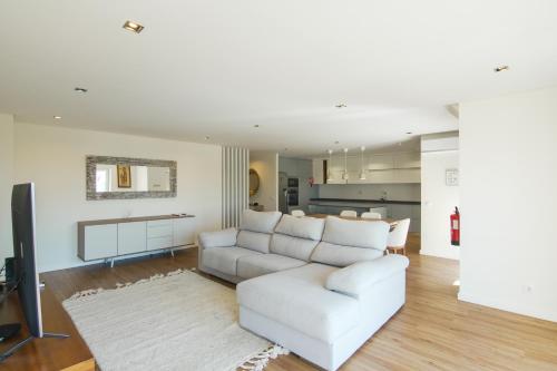 a living room with a white couch and a kitchen at Yana Luxury Home in Queluz