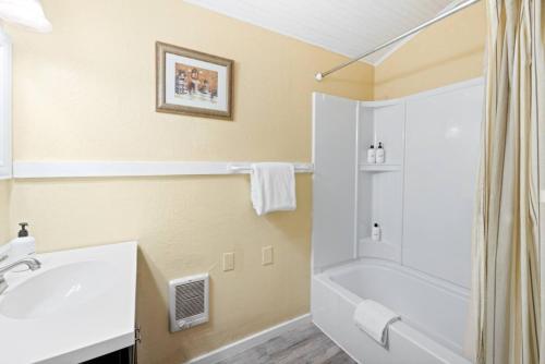 y baño con bañera blanca y ducha. en Historic Oceanside Cabin with Peek-a-boo views dog friendly, en Oceanside