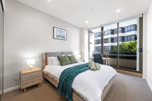 a bedroom with a bed and a large window at Prime Mascot 2BR Pool Gym Sauna Access in Sydney