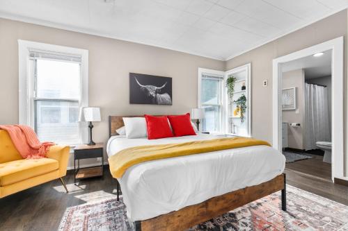 a bedroom with a large bed and a yellow chair at Roomy Central Hub, Games, Fire Pit & Downtown Fun in Oshkosh