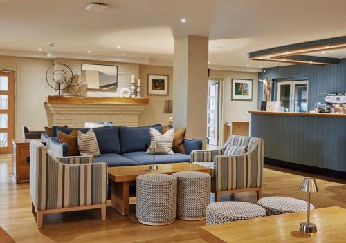 a living room with a blue couch and chairs at St Brides Spa Hotel & Village Apartments in Saundersfoot