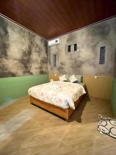 une chambre avec un lit et un tableau au mur dans l'établissement Ijen Backpacker Atas Angin dekat Stasiun Banyuwangi Kota, à Giri