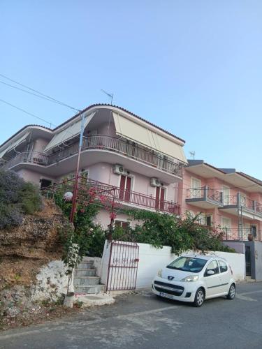 a white car parked in front of a pink building at The Spring House in Tiros