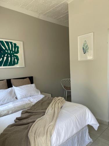 a bedroom with two beds and a chair at Lani Accommodation in Pretoria