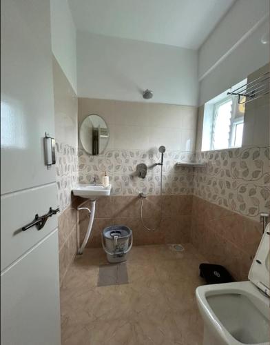 a bathroom with a toilet and a sink at The Grand Inn - Kempegowda Airport Bangalore in Devanhalli