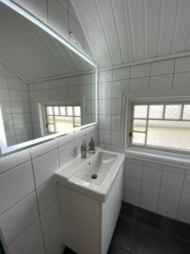 a white bathroom with a sink and a mirror at Centrally located 6-room detached house in Haugesund
