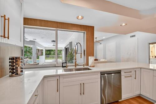 a kitchen with white cabinets and a large window at Palm Beach Polo & PGA Retreat - Pool & Luxe Comfort in Wellington
