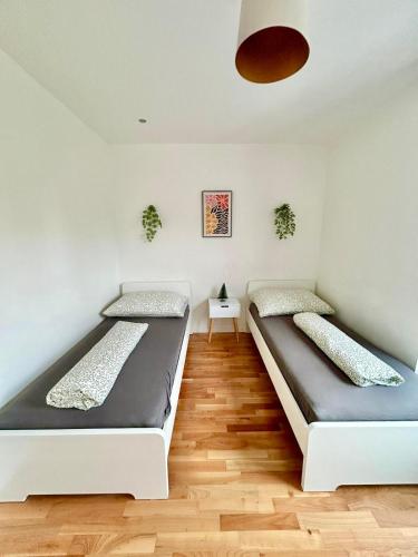 two beds in a room with wooden floors at Spacious Modern Apartment with Free Parking in Gerasdorf bei Wien