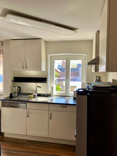 a kitchen with white cabinets and a window at Apartment Versteck am Hug in Jüterbog