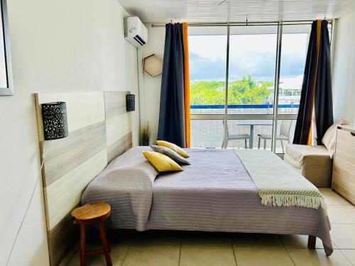 a bedroom with a bed and a large window at Soleilcaraïbe Studio - direct beach access Gosier in Le Gosier
