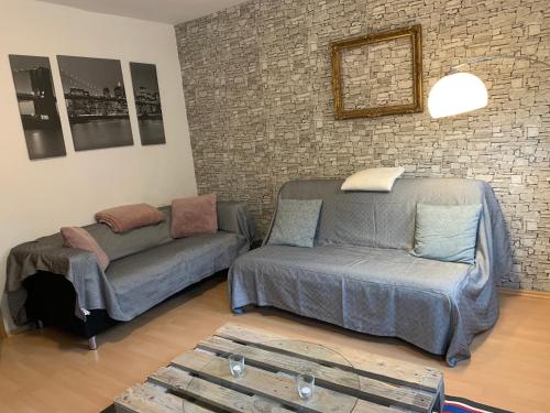 ein Wohnzimmer mit einer Couch, einer Couch und einer Backsteinwand in der Unterkunft Moderne Ferienwohnung - Top Lage nahe Skigebiet & Wanderwegen in Sankt Andreasberg