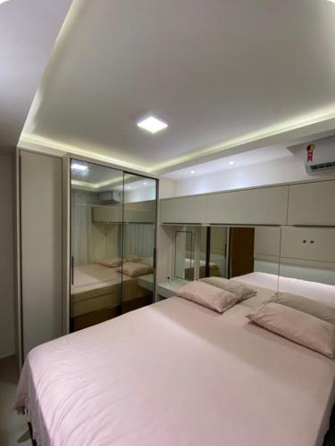 a bedroom with a large white bed with glass walls at Seu Refúgio em São Luís MA in São Luís