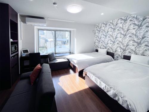 ein Hotelzimmer mit zwei Betten und einer Couch in der Unterkunft SA Inn Nagano Nakagosho - Vacation STAY 45417v in Nagano