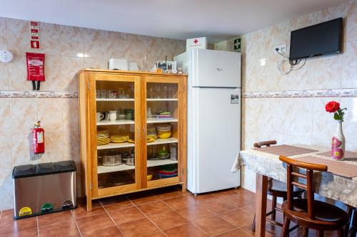 a kitchen with a white refrigerator and a table with chairs at Villa Fontes 7 in Ponta Delgada