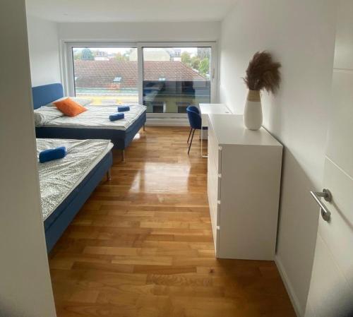 a room with two beds and a table and a desk at Luxury Apartment with Balcony & Free Parking in Vienna