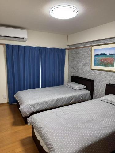 zwei Betten in einem Hotelzimmer mit blauen Vorhängen in der Unterkunft HYGGE HOUSE Tabibitonoie - Vacation STAY 61141v in Kashiwa