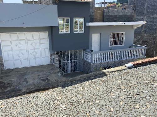 een huis met witte garagedeuren en een stenen oprit bij Casa Nova Montrond in São Filipe