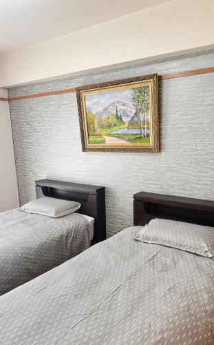 ein Schlafzimmer mit zwei Betten und einem Gemälde an der Wand in der Unterkunft HYGGE HOUSE Tabibitonoie - Vacation STAY 61173v in Kashiwa