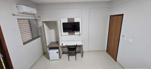 a room with a desk with a chair and a television at Hotel Ideal 5 in Araguaína