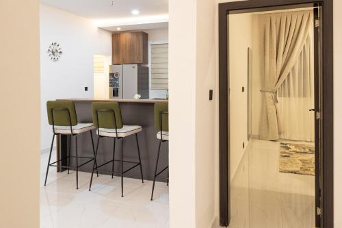 a kitchen with a bar with green stools at Greyasset Amber in Spintex