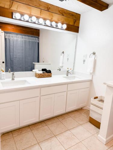 Un baño con dos lavabos y un espejo grande. en Enchanted Oaks Lakehouse, en Enchanted Oaks