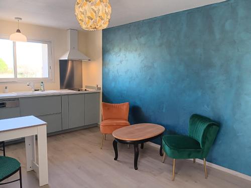 une cuisine avec une table et des chaises et un mur bleu dans l'établissement La Batisse, à Livron-sur-Drôme