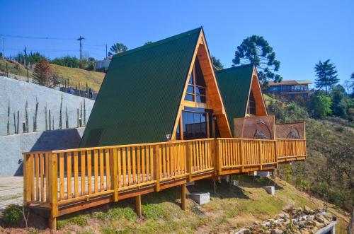 a house with a green roof on top of a hill at Chalés Laraland in Campos do Jordão
