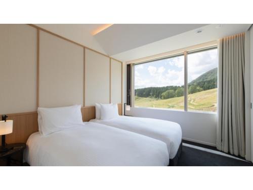 deux lits dans une chambre avec une grande fenêtre dans l'établissement Skye Niseko - Vacation STAY 33465v, à Niseko