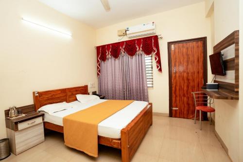 a bedroom with a bed and a television in it at Kukke Sai Skanda in Subrahmanya