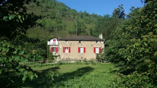une vieille maison avec volets rouges sur une colline dans l'établissement Les Cèdres Bleus de Joany, à Viviez
