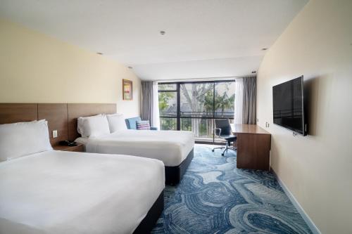 a hotel room with two beds and a flat screen tv at Holiday Inn Auckland Airport by IHG in Auckland