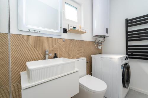 a white bathroom with a toilet and a sink at Patrikabin in Tata