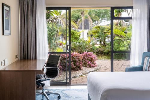 a hotel room with a desk and a bed and a window at Holiday Inn Auckland Airport by IHG in Auckland